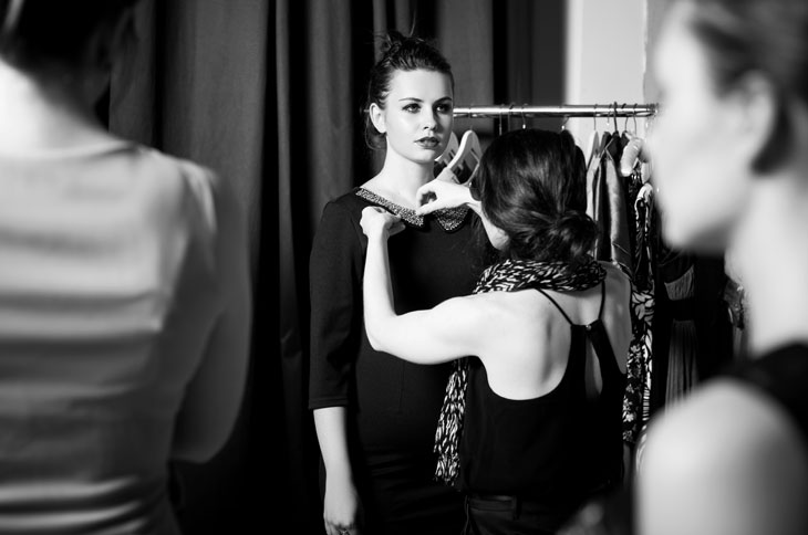 Photo en noir et blanc d'une jeune femme dont la robe est ajustée par une couturière